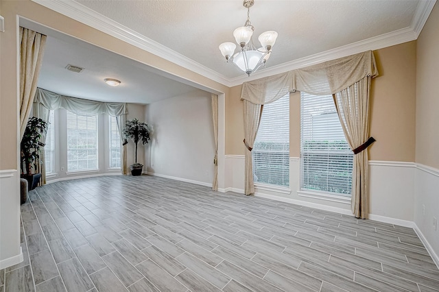 unfurnished room with ornamental molding, a wealth of natural light, and a notable chandelier