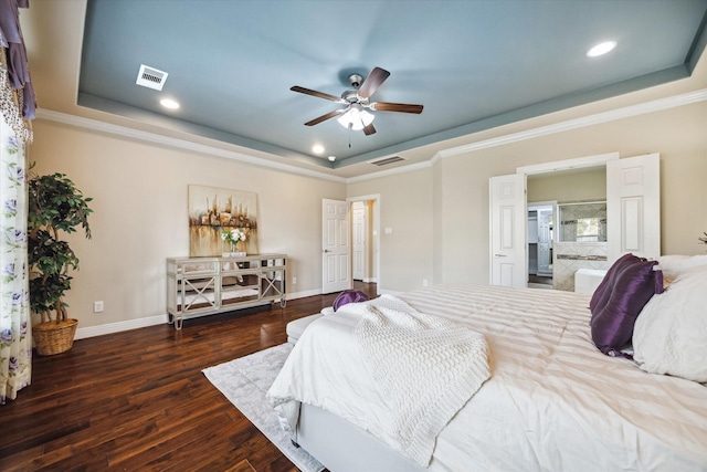 bedroom with dark wood-type flooring, connected bathroom, ceiling fan, and a tray ceiling