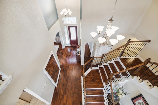 entryway with an inviting chandelier, a towering ceiling, and hardwood / wood-style flooring