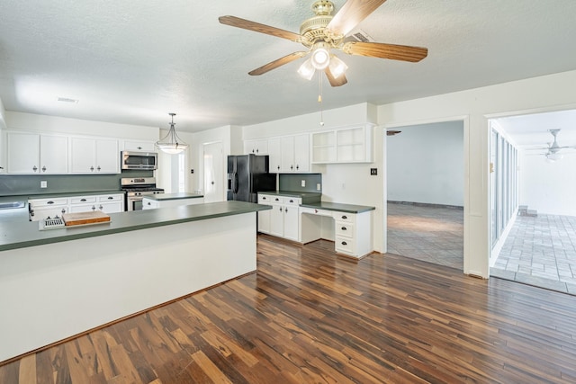 kitchen with dark wood-type flooring, a textured ceiling, pendant lighting, stainless steel appliances, and white cabinets