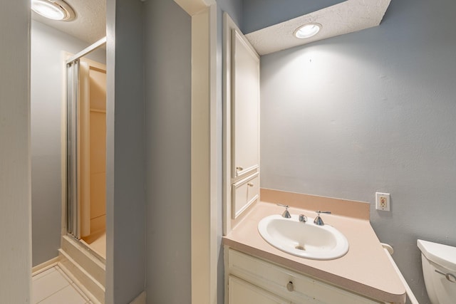 bathroom with tile patterned flooring, vanity, an enclosed shower, a textured ceiling, and toilet