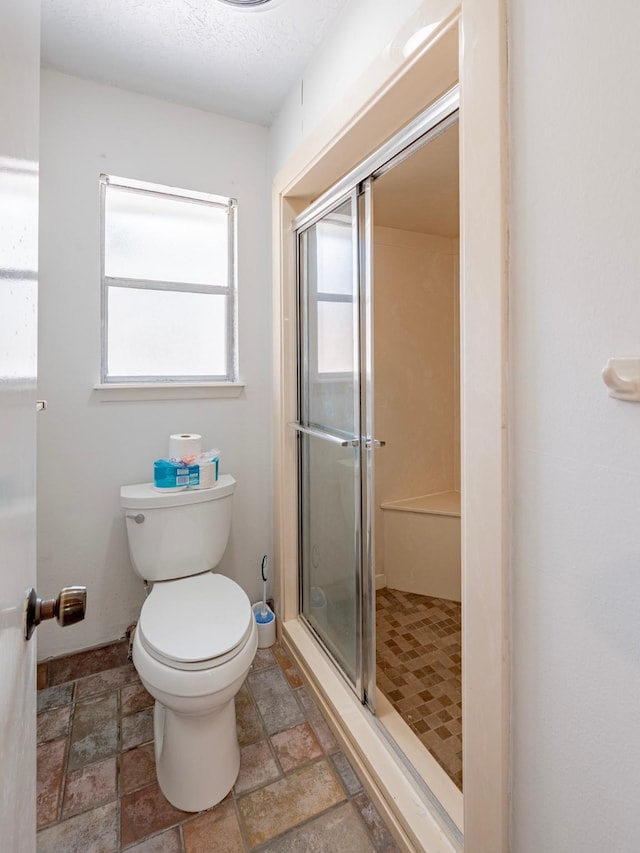 bathroom with a shower with shower door and toilet