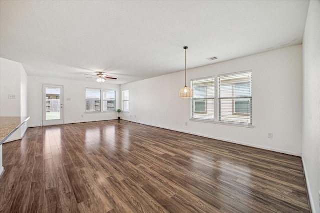 unfurnished living room with ceiling fan, a healthy amount of sunlight, and dark hardwood / wood-style floors