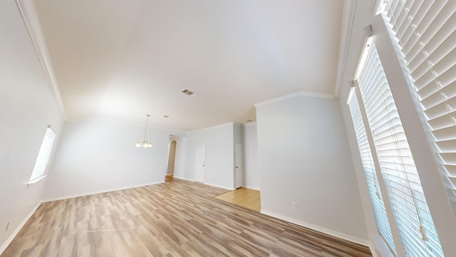 unfurnished living room featuring ornamental molding, a healthy amount of sunlight, a notable chandelier, and light wood-type flooring