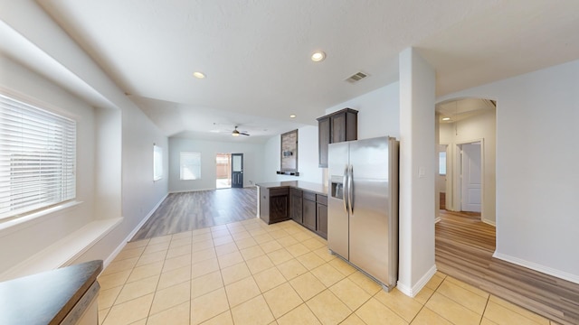 kitchen featuring kitchen peninsula, stainless steel fridge, light tile patterned floors, ceiling fan, and dark brown cabinetry