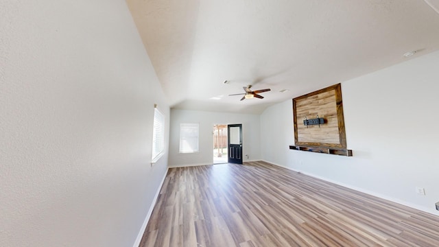 unfurnished living room featuring vaulted ceiling, light hardwood / wood-style floors, and ceiling fan