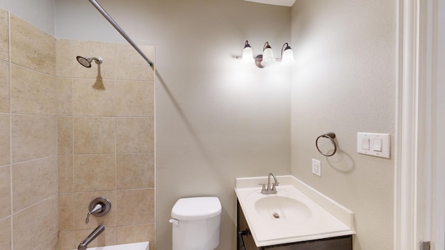 full bathroom featuring vanity, tiled shower / bath combo, and toilet