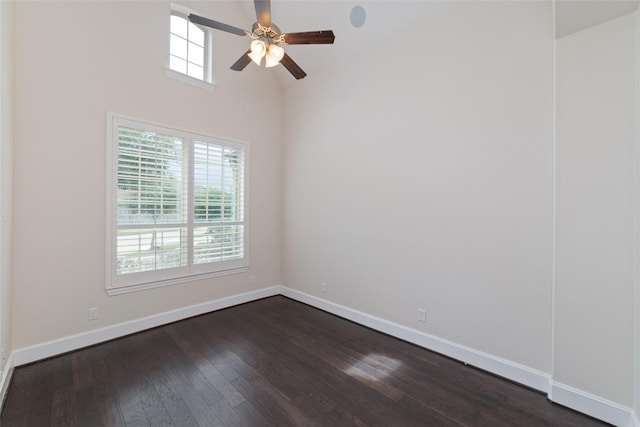 spare room with dark wood-type flooring, ceiling fan, and a towering ceiling