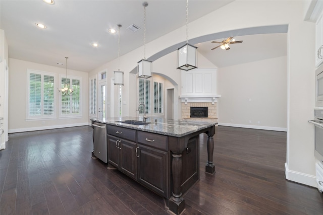 kitchen featuring a kitchen bar, hanging light fixtures, dark brown cabinets, an island with sink, and stainless steel appliances