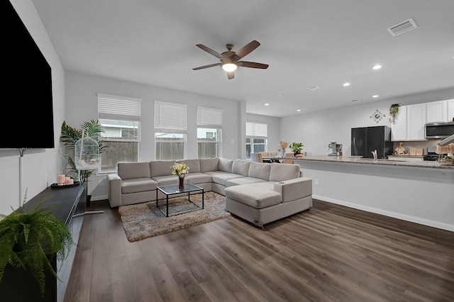 living room featuring sink, dark wood-type flooring, and ceiling fan