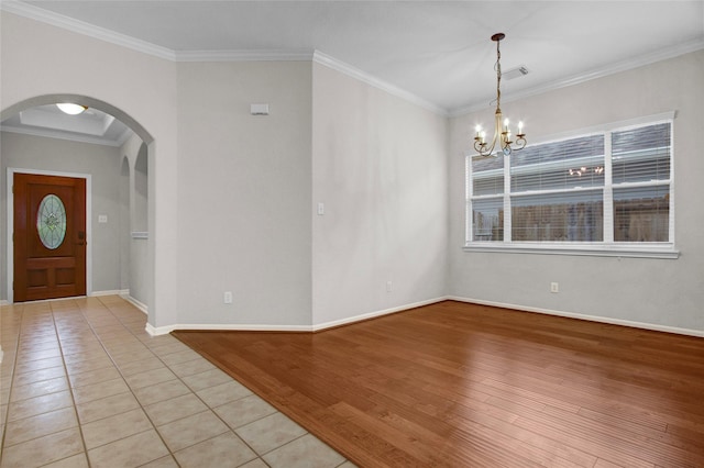 tiled entryway featuring ornamental molding and an inviting chandelier