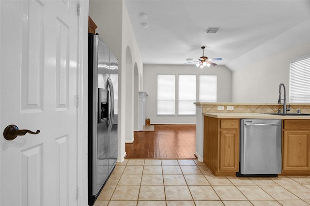 kitchen featuring lofted ceiling, sink, light tile patterned floors, ceiling fan, and stainless steel appliances