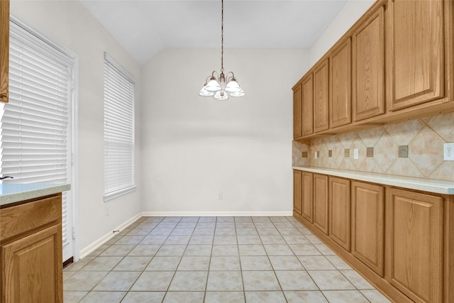 kitchen with light tile patterned flooring, lofted ceiling, backsplash, and decorative light fixtures