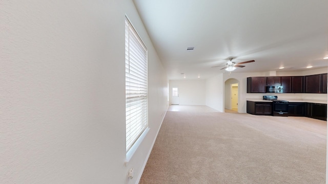 unfurnished living room featuring plenty of natural light, light carpet, and ceiling fan