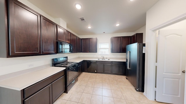 kitchen with sink, light tile patterned floors, dark brown cabinetry, and black appliances