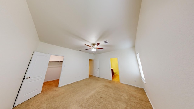 unfurnished bedroom featuring ceiling fan, connected bathroom, a spacious closet, light colored carpet, and a closet