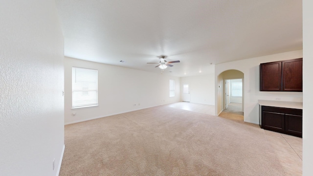 unfurnished living room featuring plenty of natural light, light colored carpet, and ceiling fan