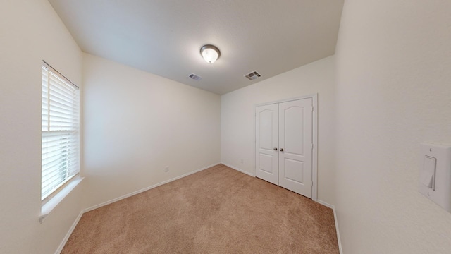 unfurnished bedroom featuring light colored carpet and a closet