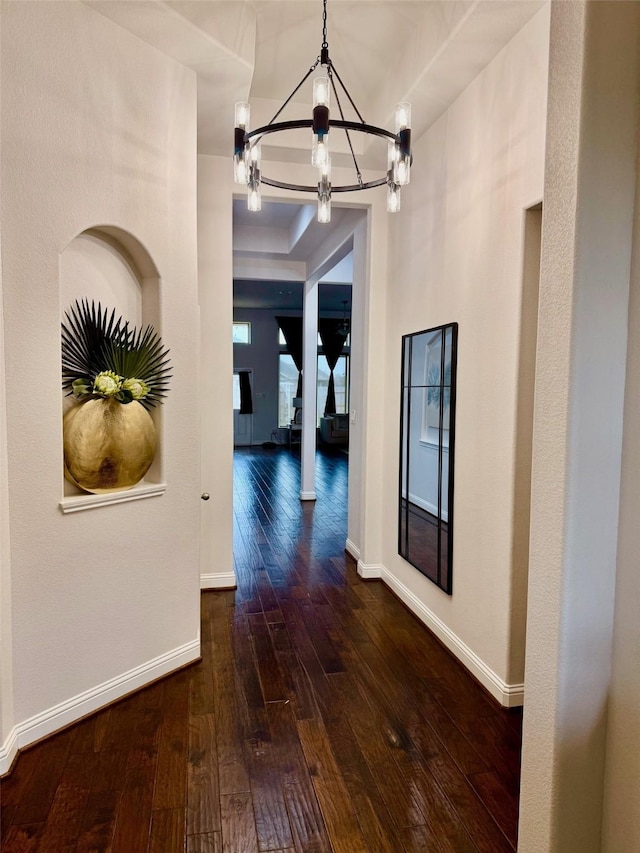 corridor with dark hardwood / wood-style flooring and a notable chandelier