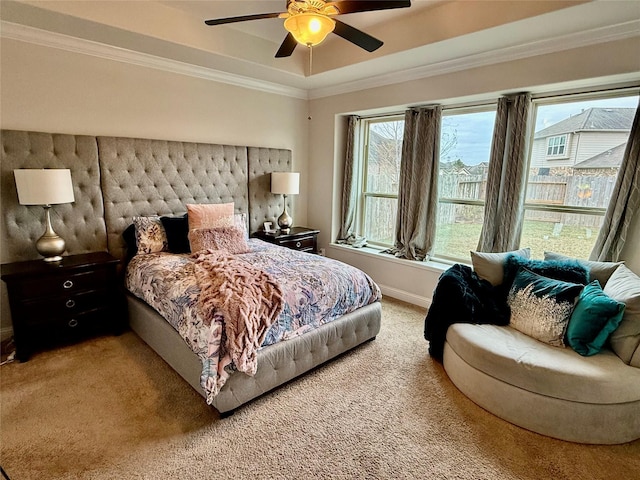 carpeted bedroom with crown molding, ceiling fan, and a tray ceiling