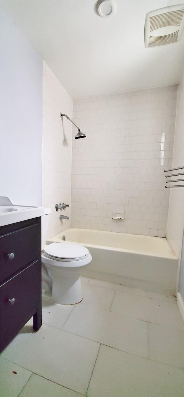 full bathroom with tile patterned flooring, tiled shower / bath, vanity, and toilet