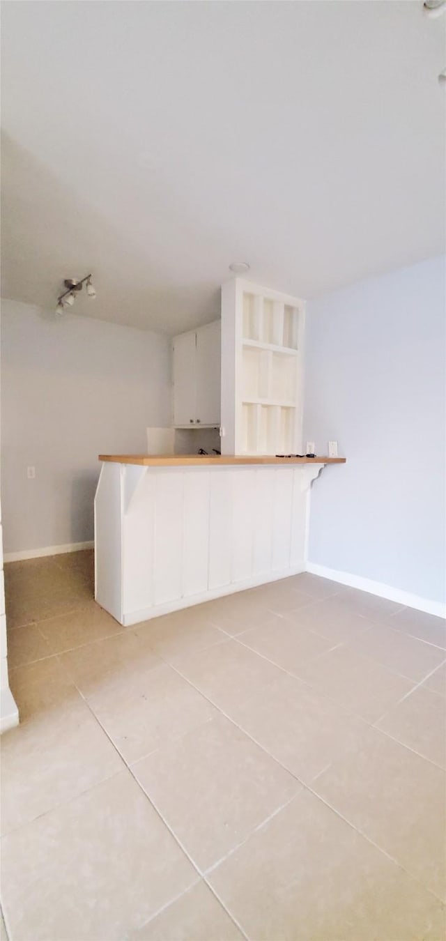 interior space with light tile patterned flooring, white cabinets, and kitchen peninsula