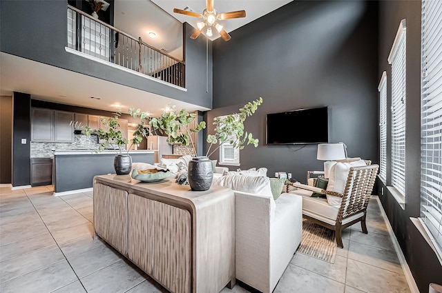 living room featuring ceiling fan, a towering ceiling, and light tile patterned floors