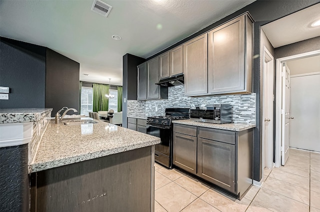 kitchen with light tile patterned flooring, sink, light stone counters, black gas range, and decorative backsplash