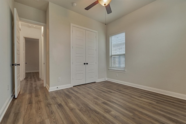 unfurnished bedroom featuring dark wood-style floors, ceiling fan, baseboards, and a closet