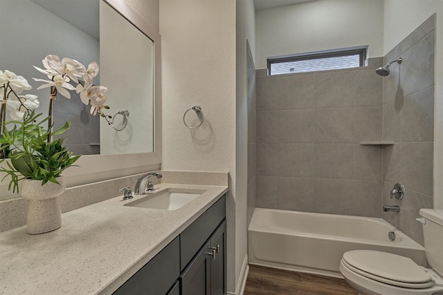 full bathroom with tiled shower / bath combo, wood-type flooring, vanity, and toilet