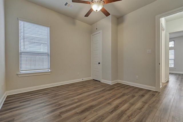 spare room with visible vents, dark wood finished floors, baseboards, and ceiling fan