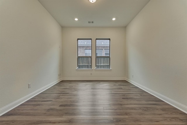 spare room with dark wood-style floors, baseboards, visible vents, and recessed lighting