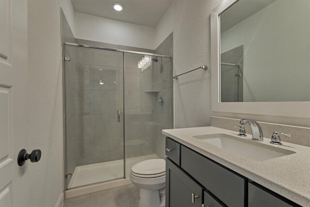 bathroom featuring vanity, toilet, an enclosed shower, and tile patterned flooring