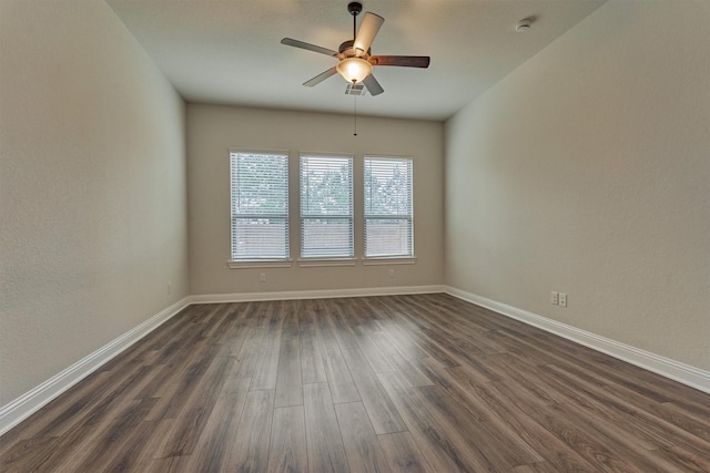 empty room featuring dark wood-type flooring, baseboards, and a ceiling fan