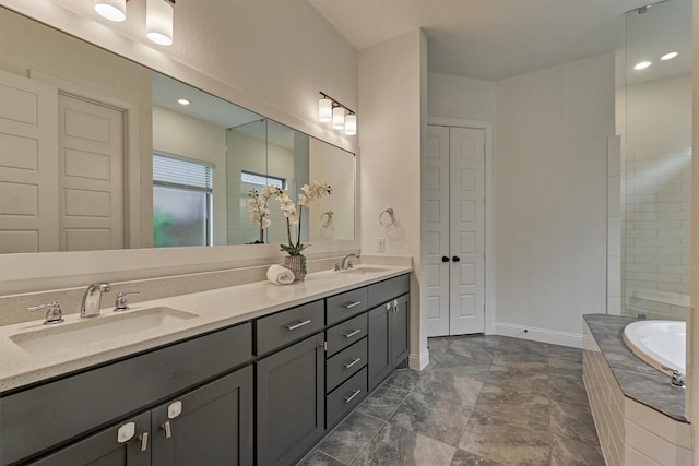 full bathroom with tiled tub, a sink, baseboards, and double vanity