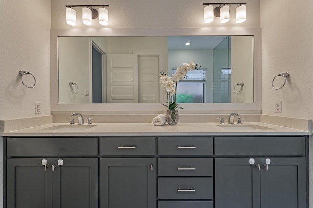 bathroom with double vanity, a sink, and a textured wall