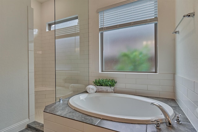 full bath featuring walk in shower, plenty of natural light, and a garden tub