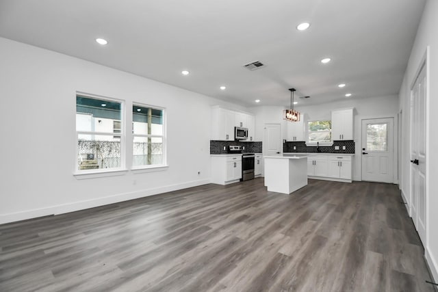 kitchen featuring appliances with stainless steel finishes, decorative light fixtures, a kitchen island, and white cabinets