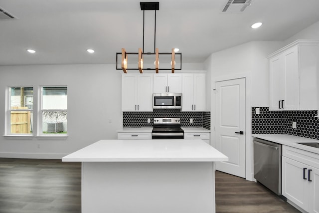 kitchen with white cabinetry, a center island, dark hardwood / wood-style flooring, pendant lighting, and stainless steel appliances