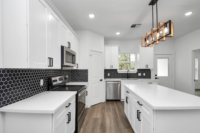 kitchen with a kitchen island, decorative light fixtures, sink, white cabinets, and stainless steel appliances