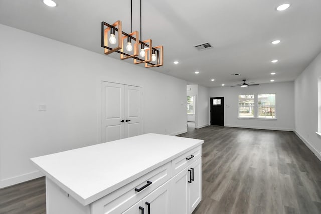 kitchen featuring ceiling fan, white cabinetry, hanging light fixtures, dark hardwood / wood-style floors, and a center island