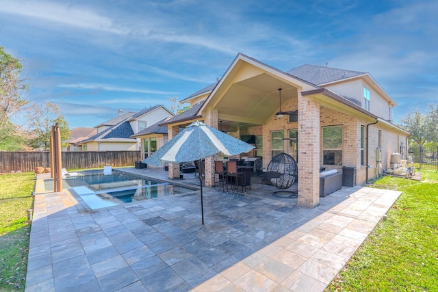 back of house featuring area for grilling, an outdoor bar, ceiling fan, a fenced in pool, and a patio