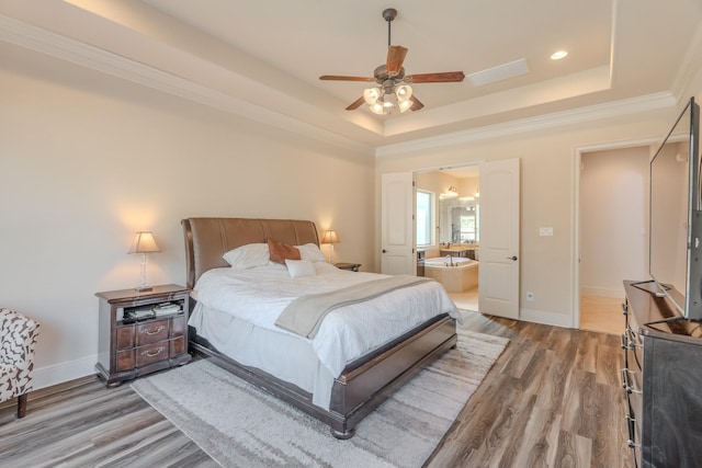 bedroom featuring ceiling fan, connected bathroom, wood-type flooring, ornamental molding, and a raised ceiling