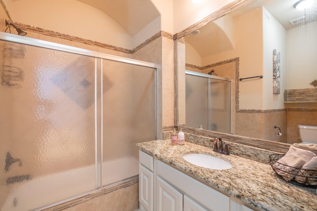 full bathroom featuring vanity, vaulted ceiling, toilet, and combined bath / shower with glass door