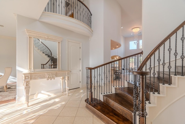 stairway with tile patterned flooring and a towering ceiling