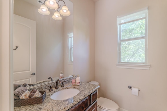 bathroom with vanity, plenty of natural light, a chandelier, and toilet