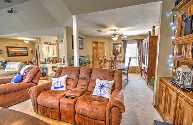 carpeted living room with ceiling fan and a textured ceiling