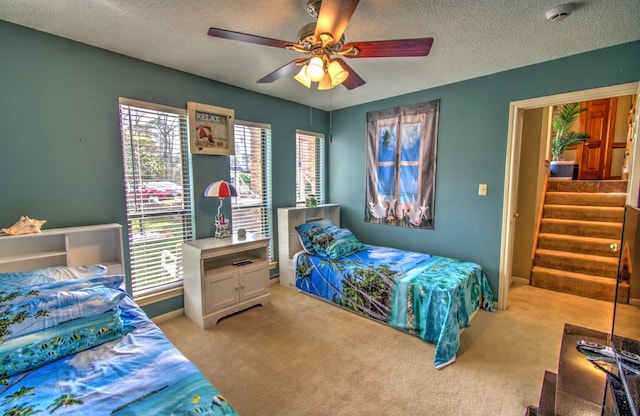 carpeted bedroom featuring ceiling fan and a textured ceiling