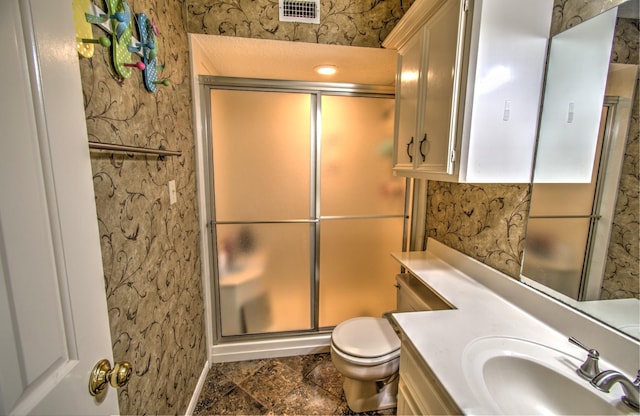 bathroom featuring vanity, toilet, and a shower with shower door