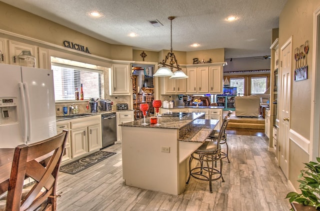 kitchen with a textured ceiling, dishwasher, a kitchen island, pendant lighting, and white refrigerator with ice dispenser